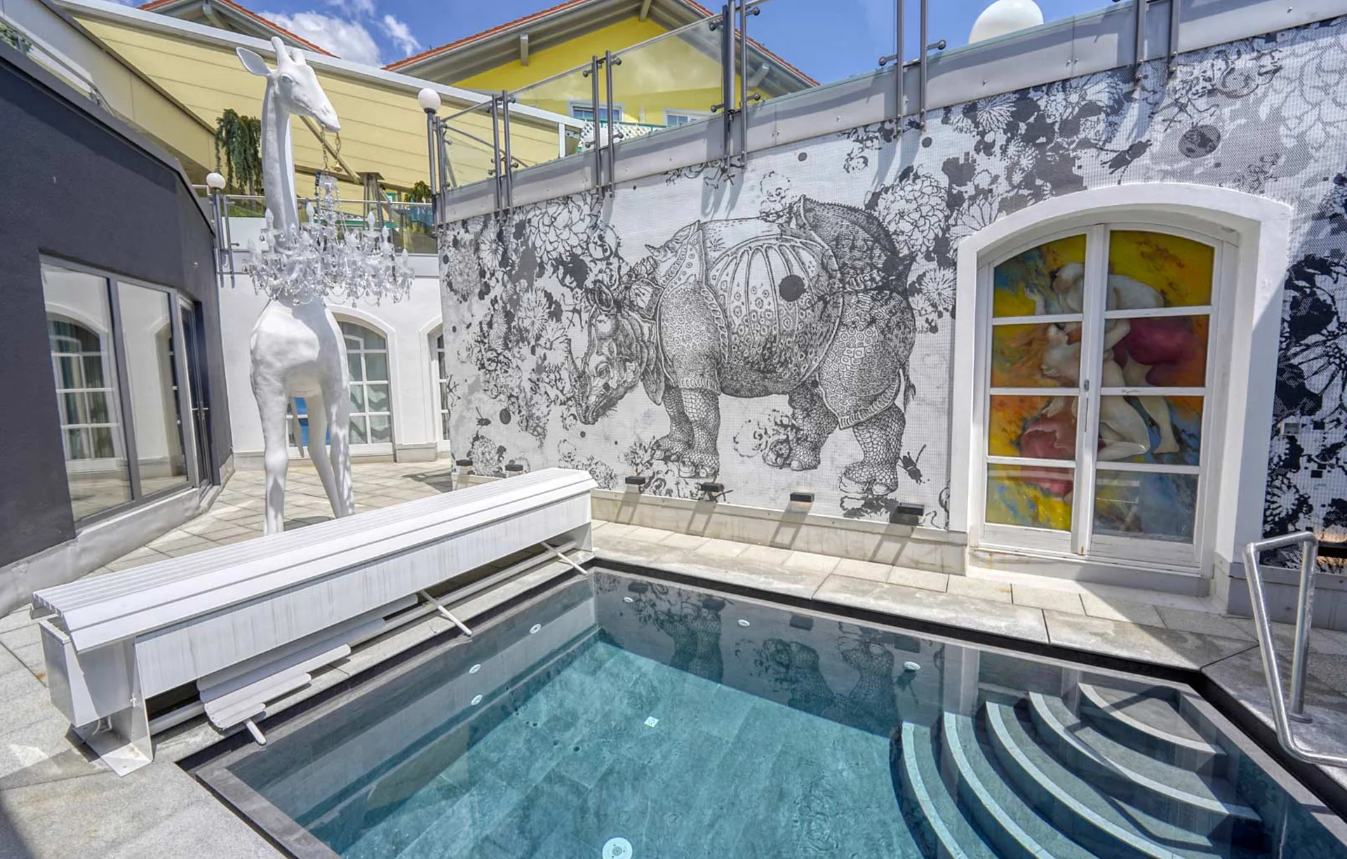 Moderner Innenhof mit Pool, weißer Giraffen-Skulptur und Kunst an der Wand