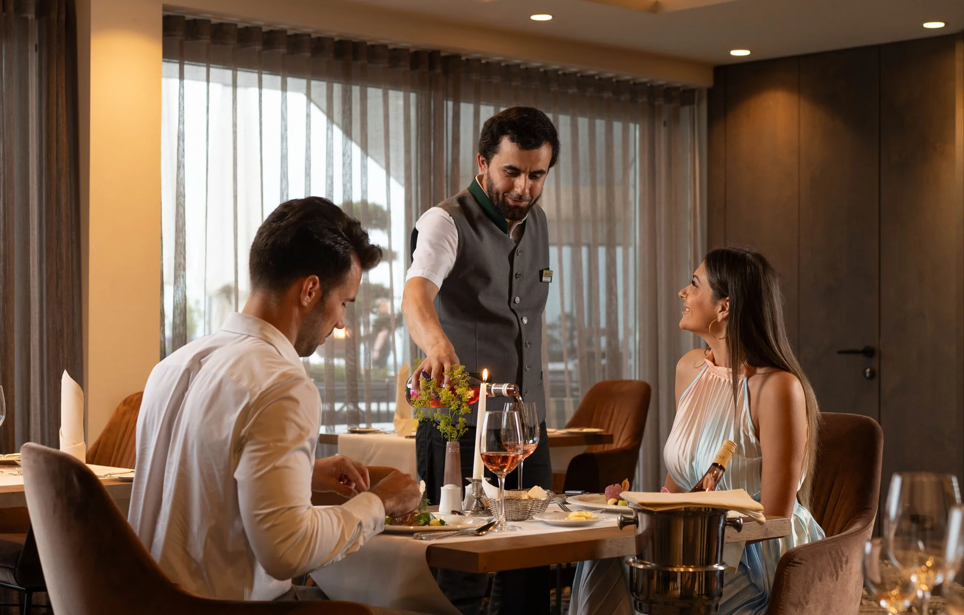 Kellner serviert Gästen Wein im eleganten Restaurant