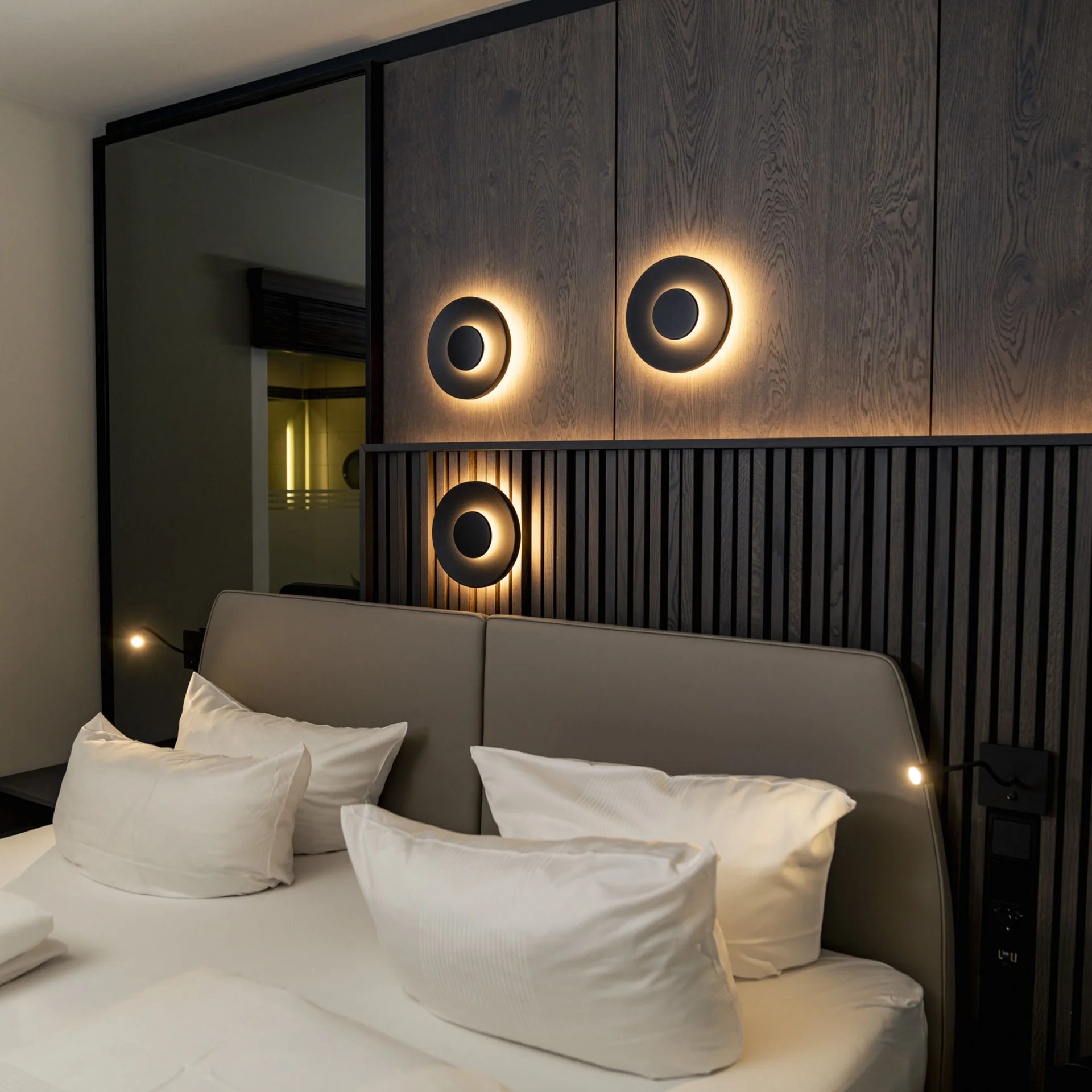 Modernes Schlafzimmer mit beleuchteten Wandlampen und weichen Kissen auf dem Bett