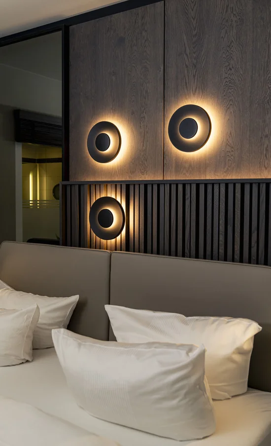 Die Adresse für Wellness in Bayern: Ihr Hotel in St. Englmar Modernes Schlafzimmer mit beleuchteten Wandlampen und weichen Kissen auf dem Bett