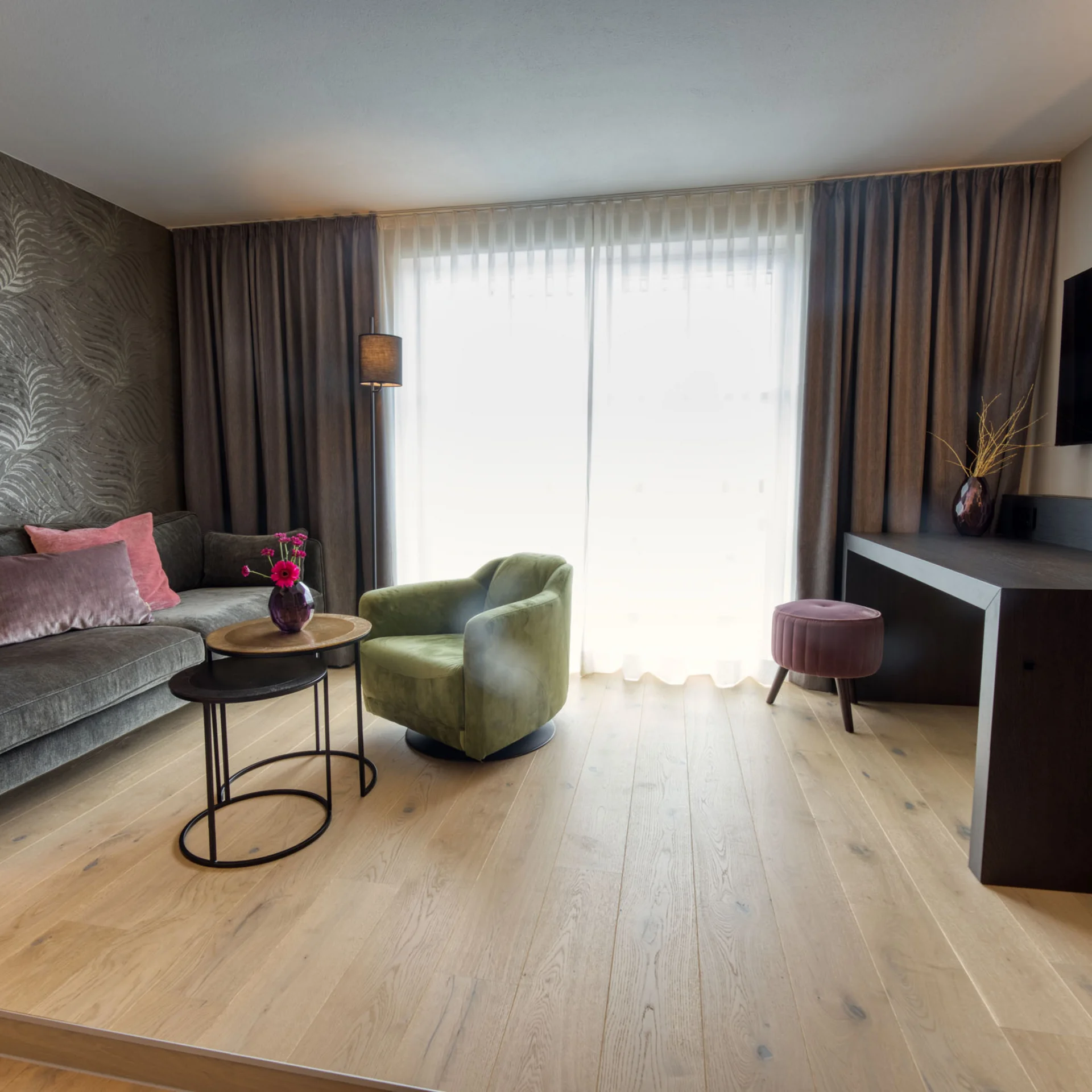 Modern eingerichtetes Wohnzimmer mit grüner Sessel und TV an der Wand