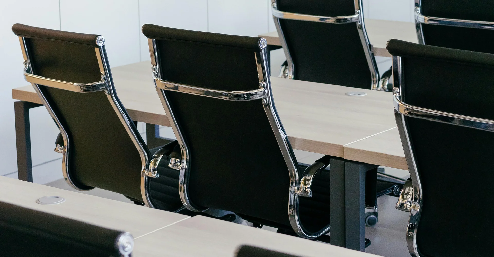 Leere moderne schwarze Bürostühle um einen Konferenztisch in hellem Raum