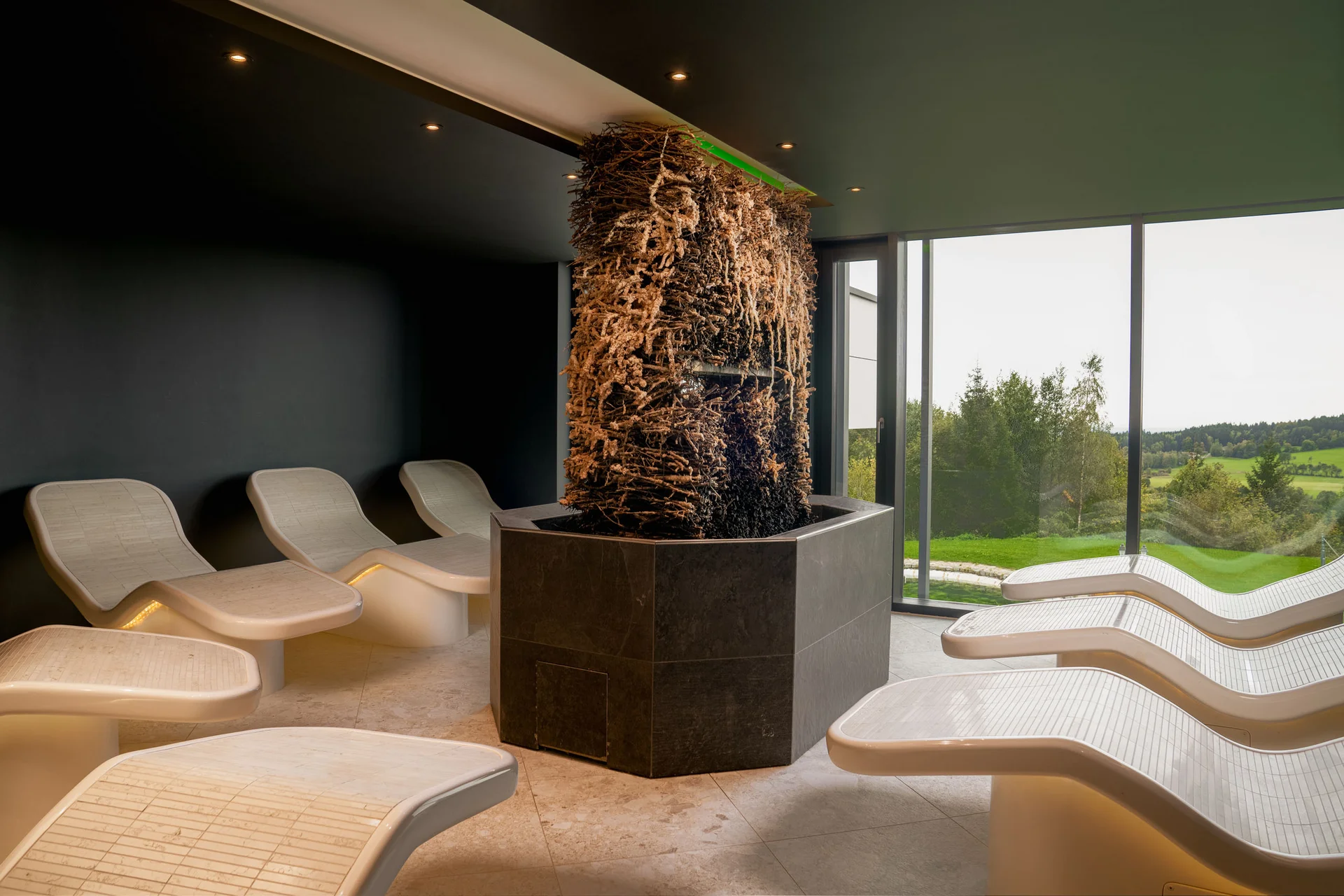 Ruheliegen um eine Säule mit hängenden Naturmaterialien in einem Raum mit Ausblick