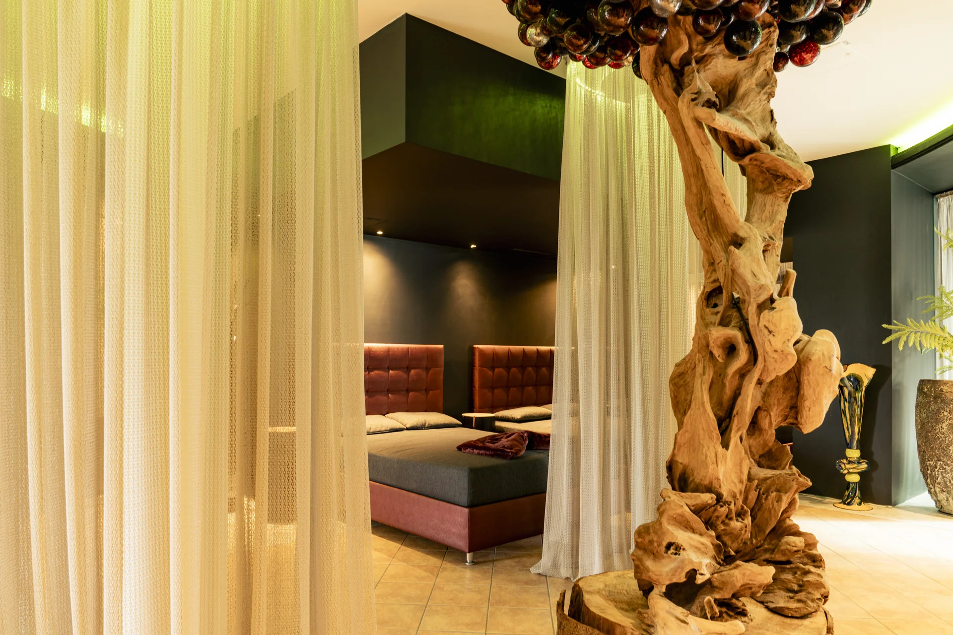 Gemütliches Schlafzimmer mit Vorhängen und dekorativem Holzskulptur