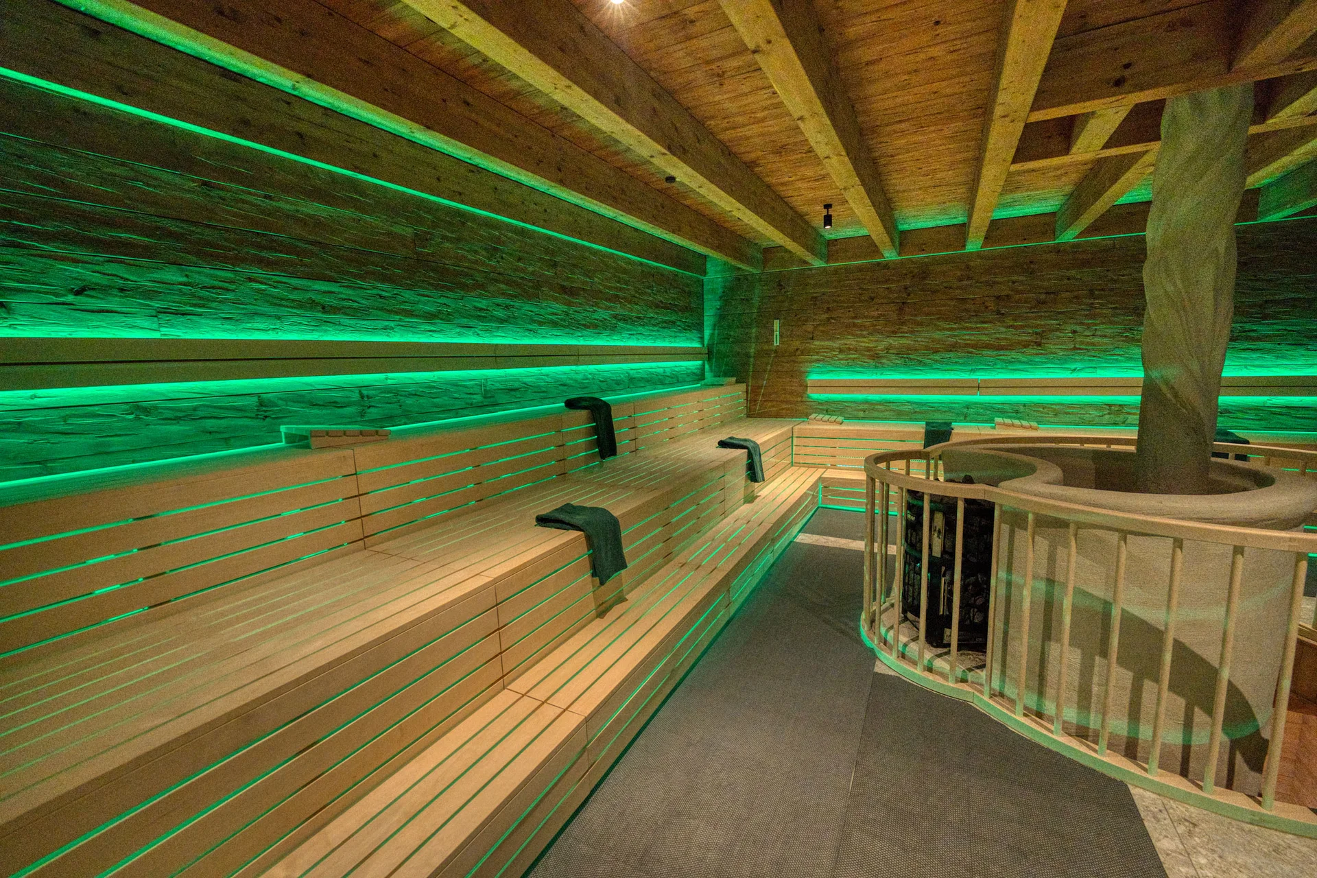 Innenraum einer Sauna mit grüner LED-Beleuchtung und Holzbänken