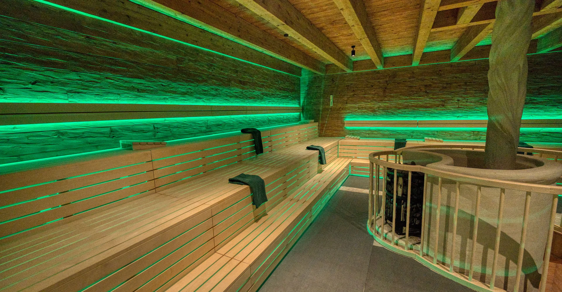 Innenraum einer Sauna mit grüner LED-Beleuchtung und Holzbänken