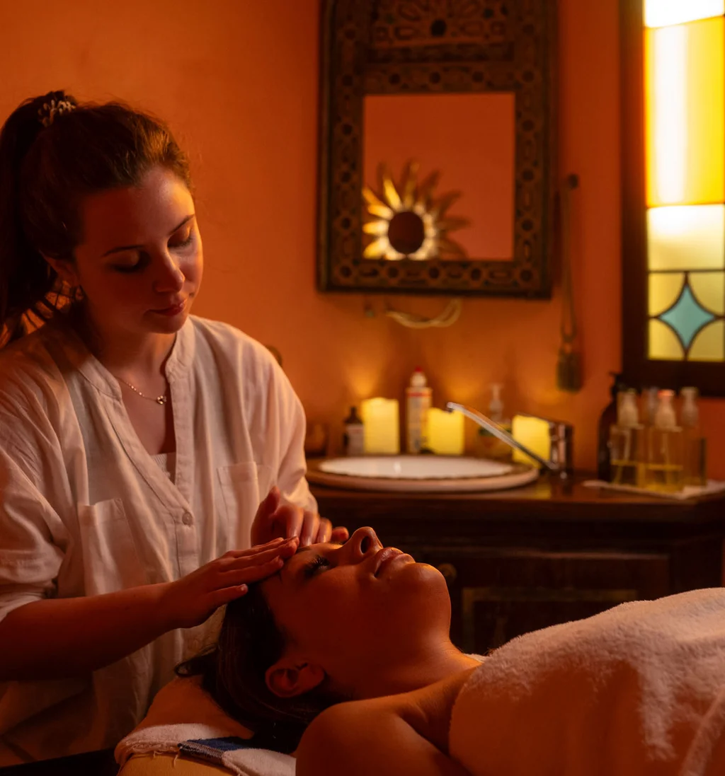 Frau erhält entspannende Gesichtsmassage in warm beleuchtetem Spa-Zimmer