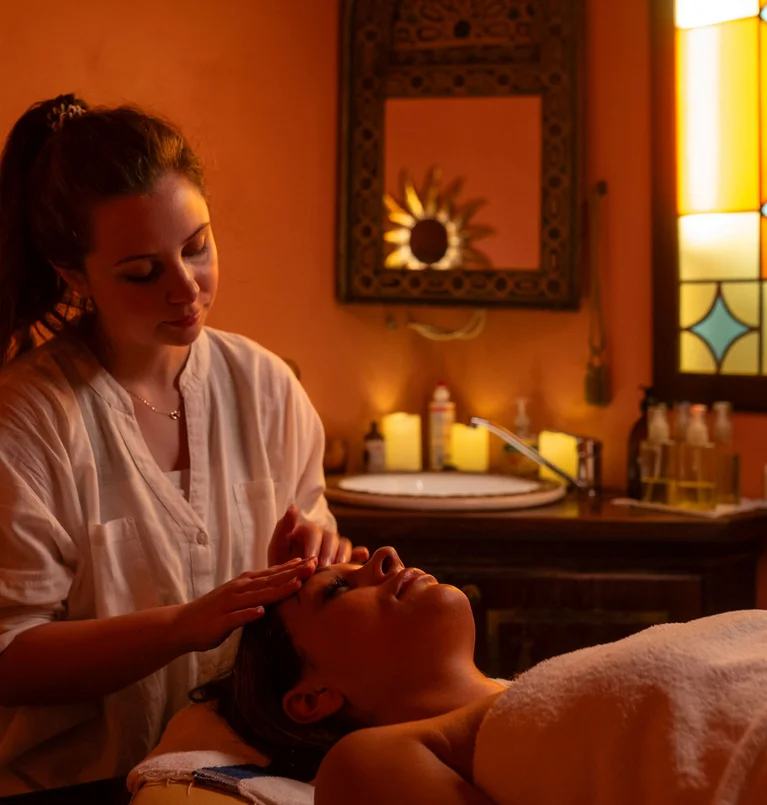 Frau erhält entspannende Gesichtsmassage in warm beleuchtetem Spa-Zimmer