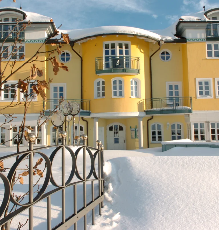 Gelbes mehrstöckiges Gebäude mit Balkonen in einer verschneiten Winterlandschaft