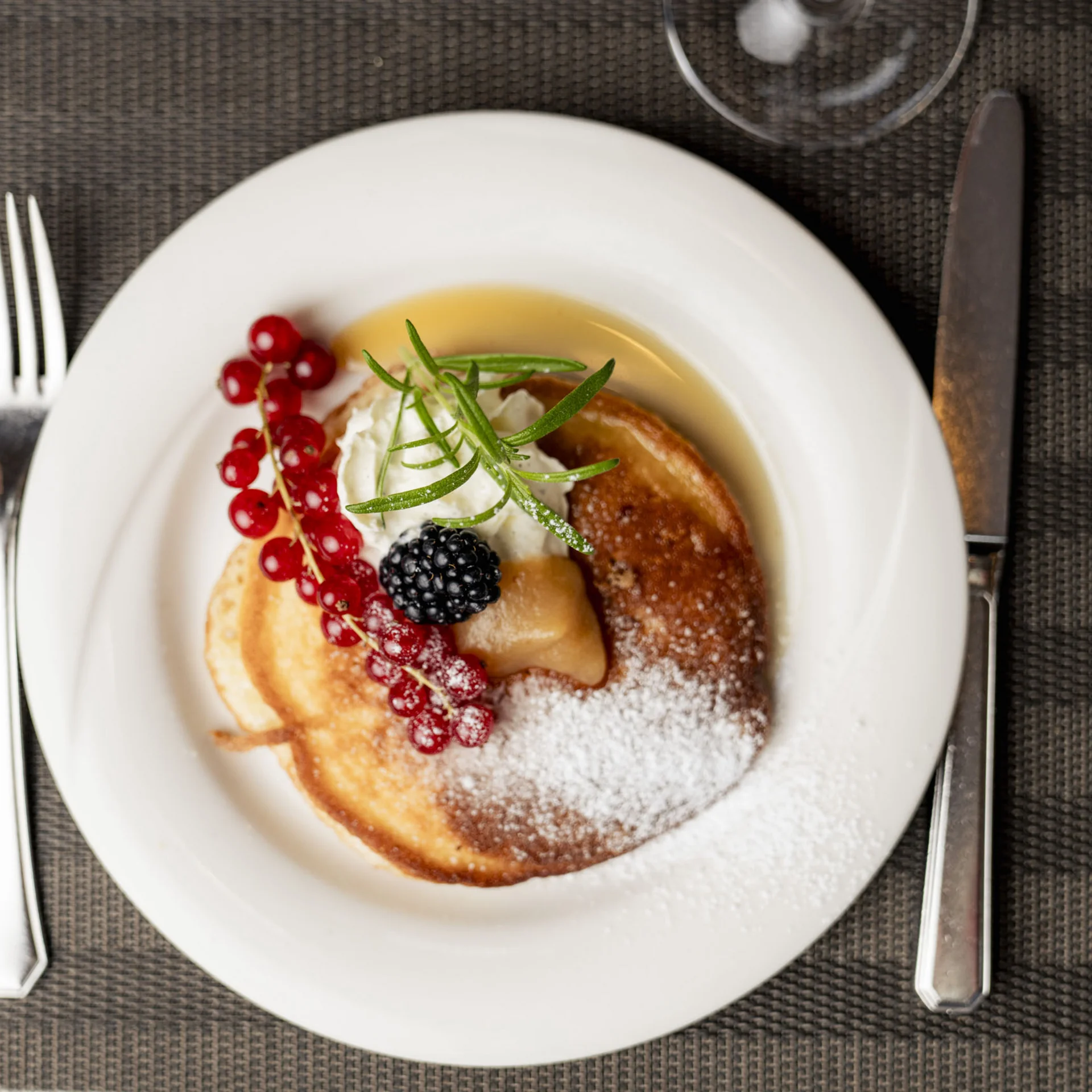 Pfannkuchen mit Beeren, Sahne und Puderzucker auf weißem Teller