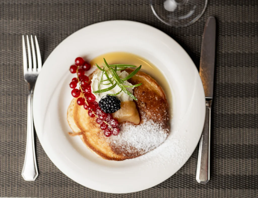 Pfannkuchen mit Beeren, Sahne und Puderzucker auf weißem Teller