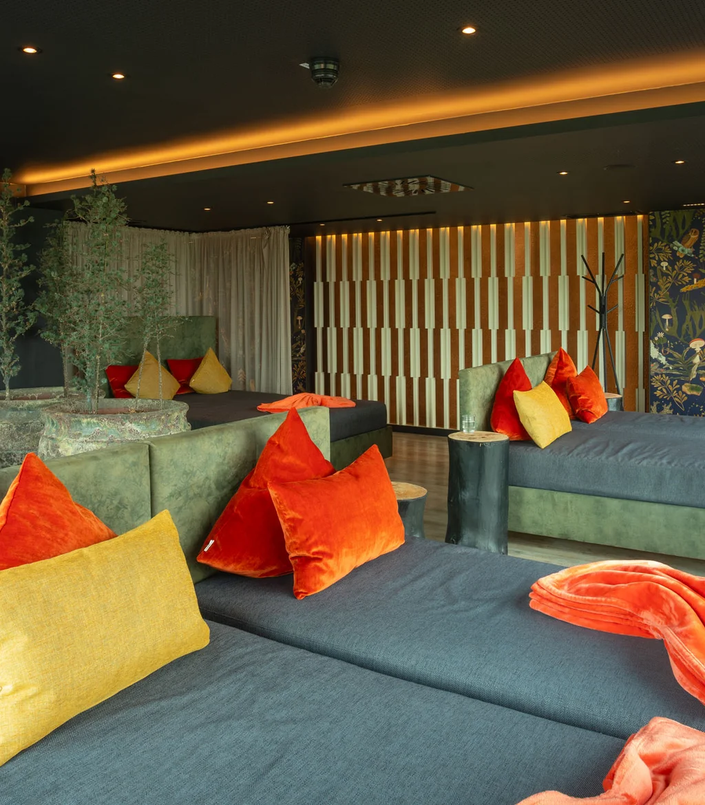 Moderne Lounge mit grünen Sofas, bunten Kissen und dekorativen Pflanzen