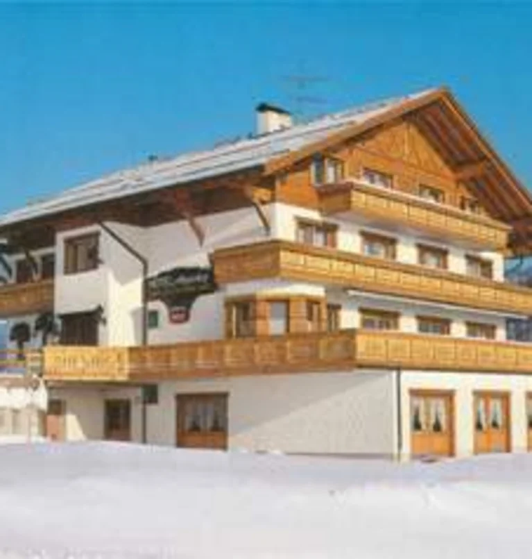 Traditionelles Chalet in schneebedeckter Winterlandschaft bei blauem Himmel