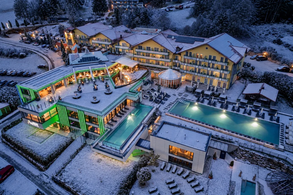 Für Feiern in kleiner und großer Runde Verschneites Hotelresort mit beleuchteten Gebäuden und Außenpools in der Dämmerung