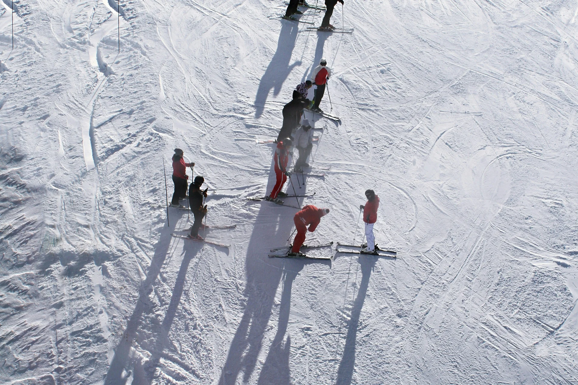 Menschen beim Skifahren auf verschneiter Piste mit langen Schatten