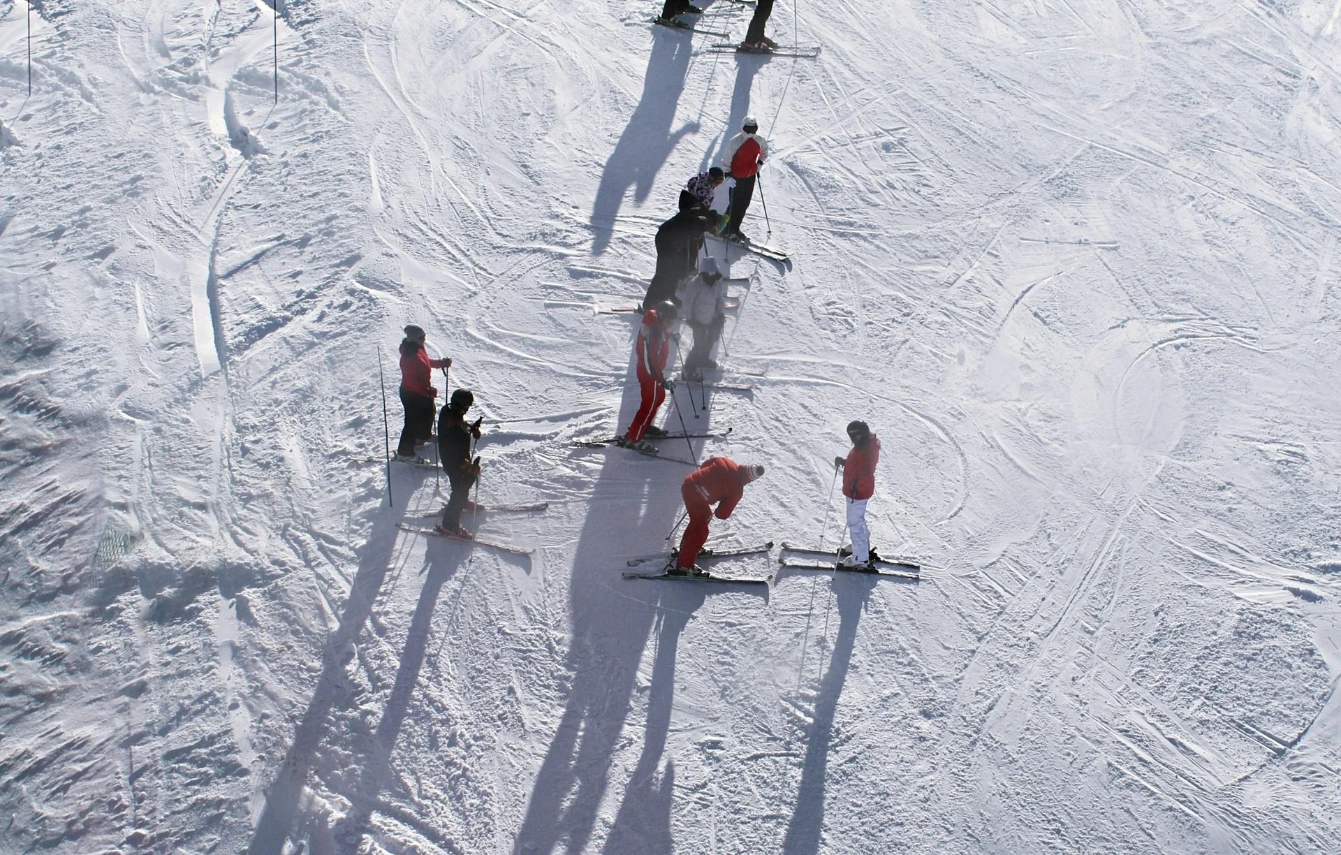 Menschen beim Skifahren auf verschneiter Piste mit langen Schatten