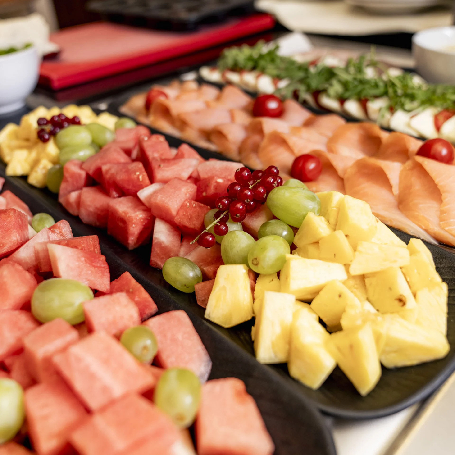 Frisches Obst und Wurst auf Servierplatten mit Salat im Hintergrund