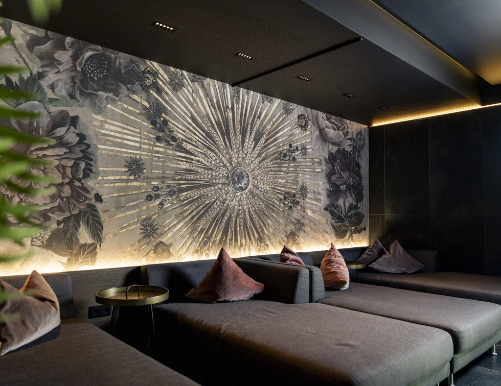Moderne Lounge mit grauen Sofas, bunten Kissen und künstlerischer Wandgestaltung