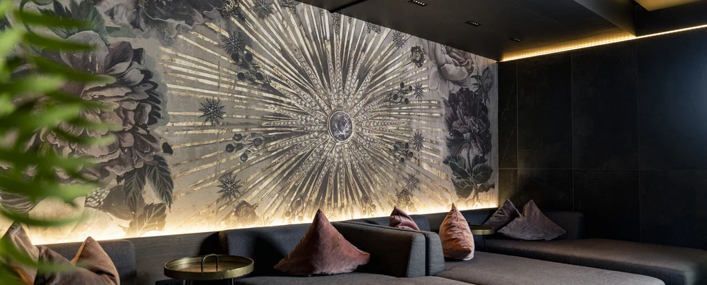 Moderne Lounge mit grauen Sofas, bunten Kissen und künstlerischer Wandgestaltung