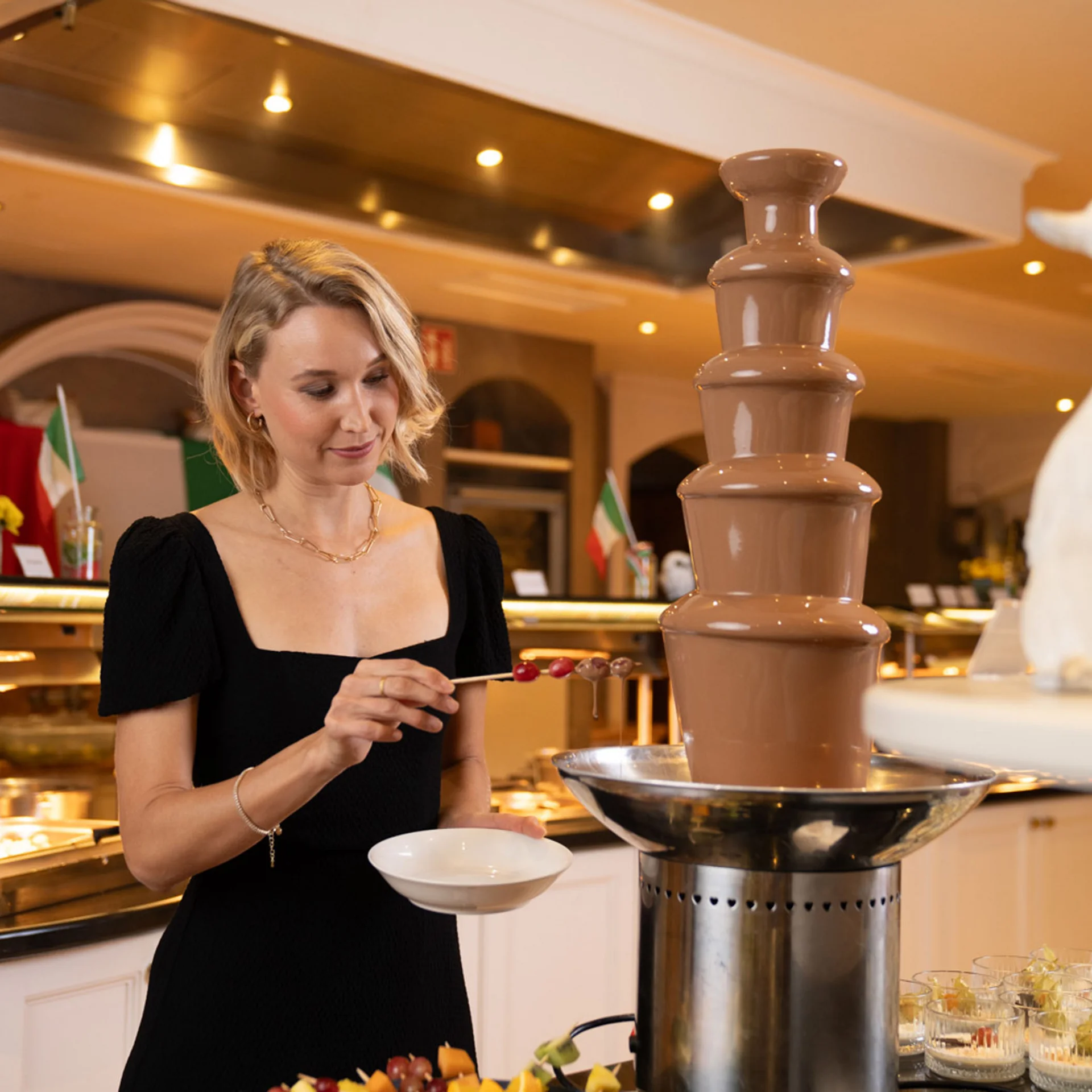 Frau taucht Früchte in Schokoladenbrunnen in Restaurant