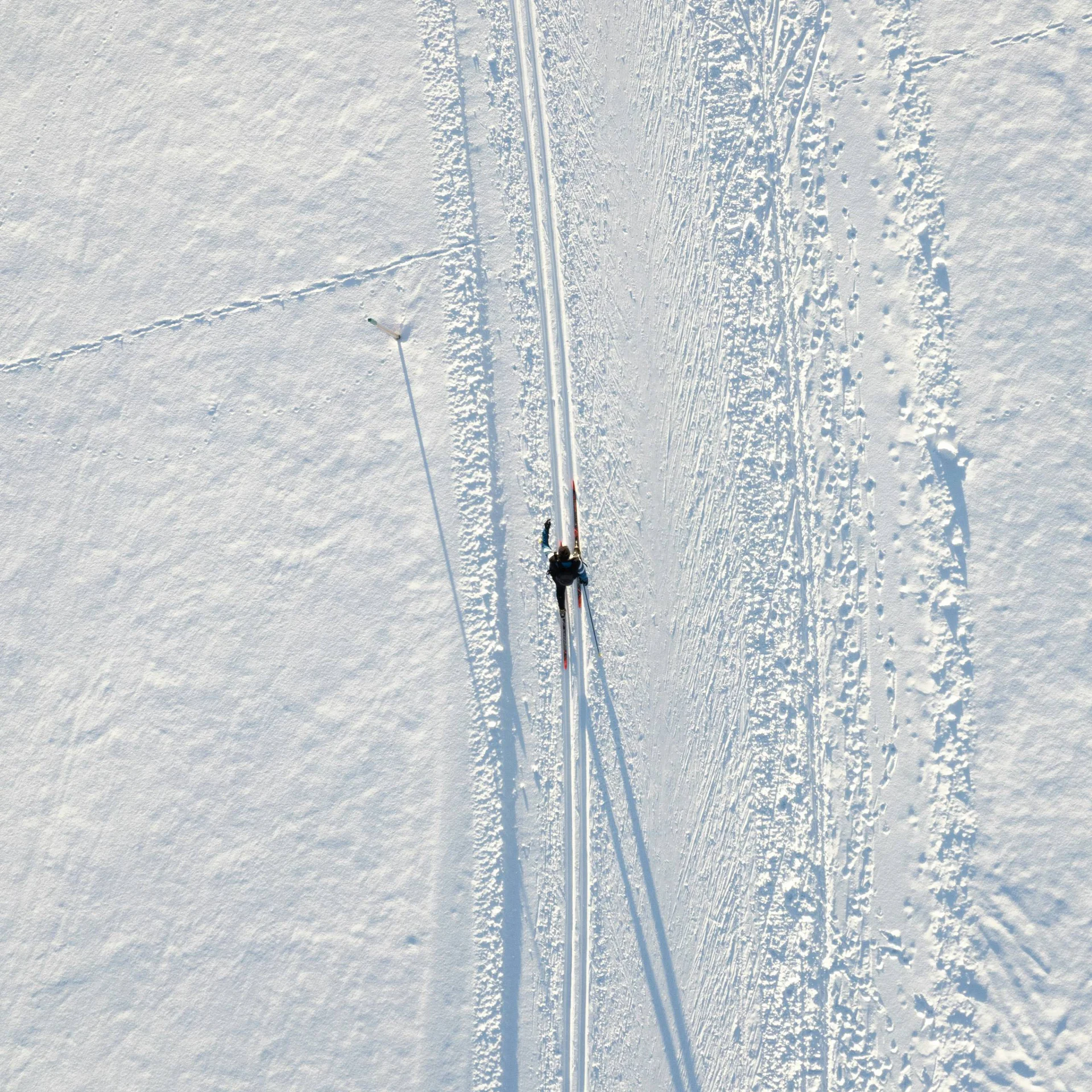 Person Langlaufen auf schneebedeckter Spur mit Windrad und Schatten