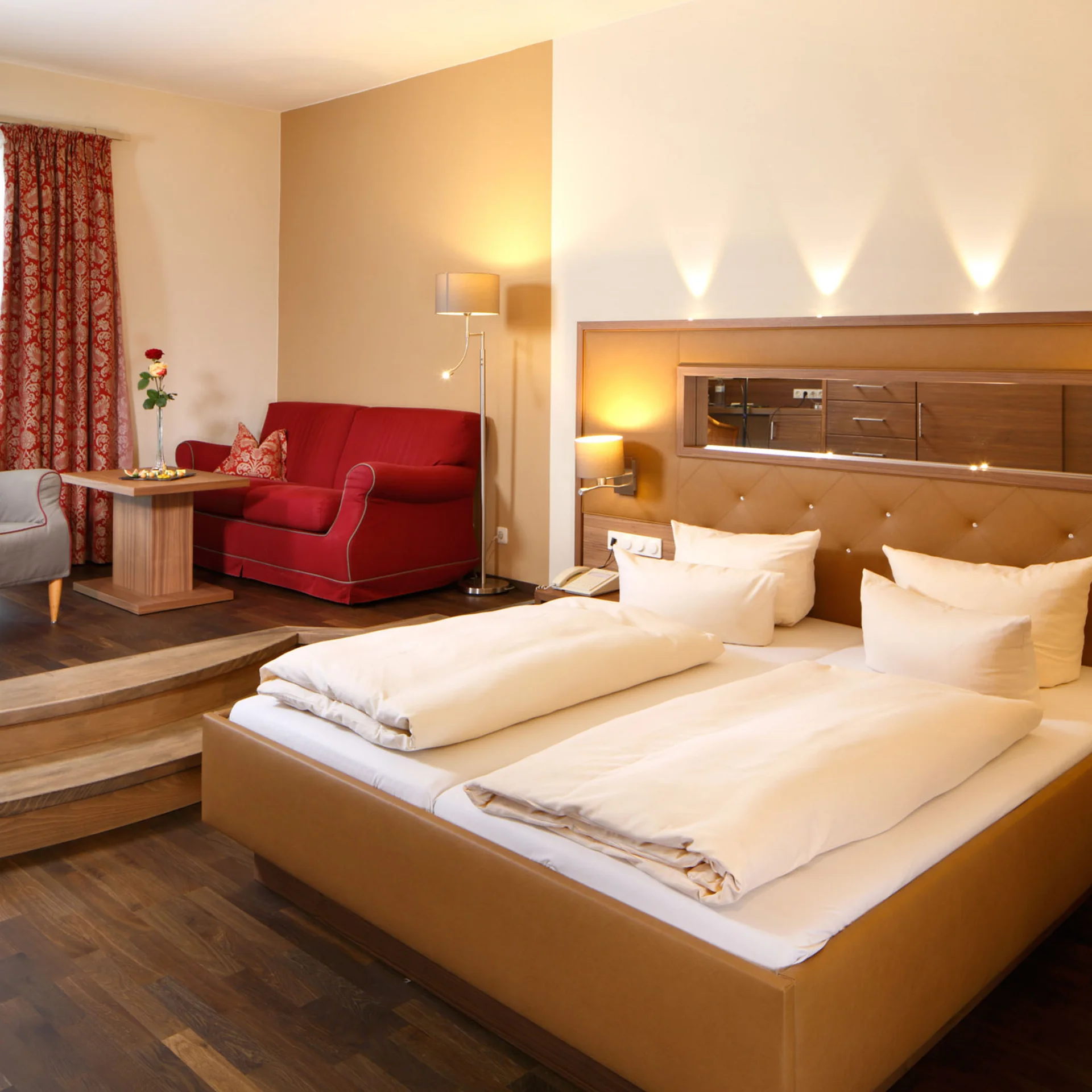 Modernes Hotelzimmer mit Doppelbett, Sofa, Sessel und indirekter Beleuchtung
