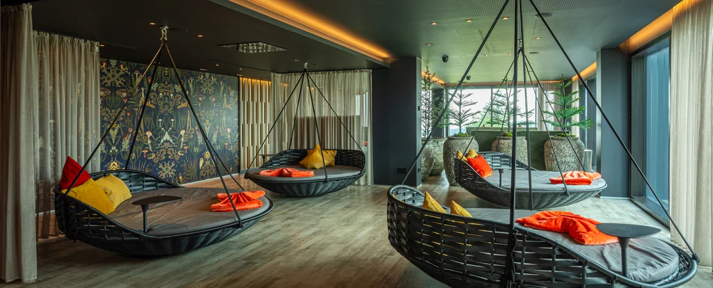 Moderner Lounge-Bereich mit Hängesesseln und bunten Kissen