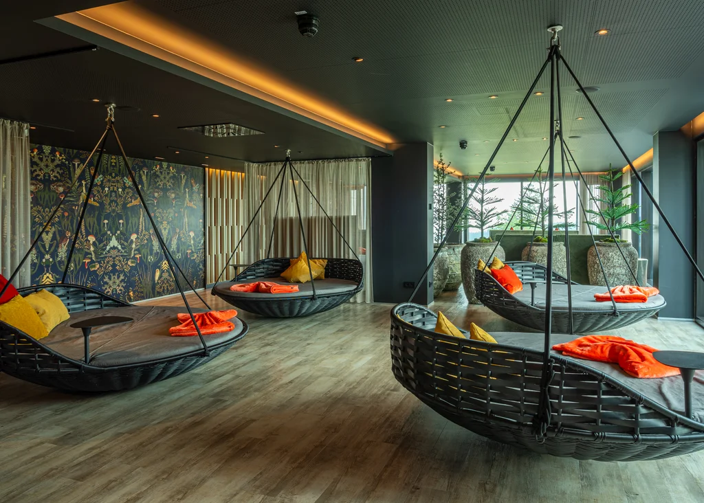 Moderner Lounge-Bereich mit Hängesesseln und bunten Kissen