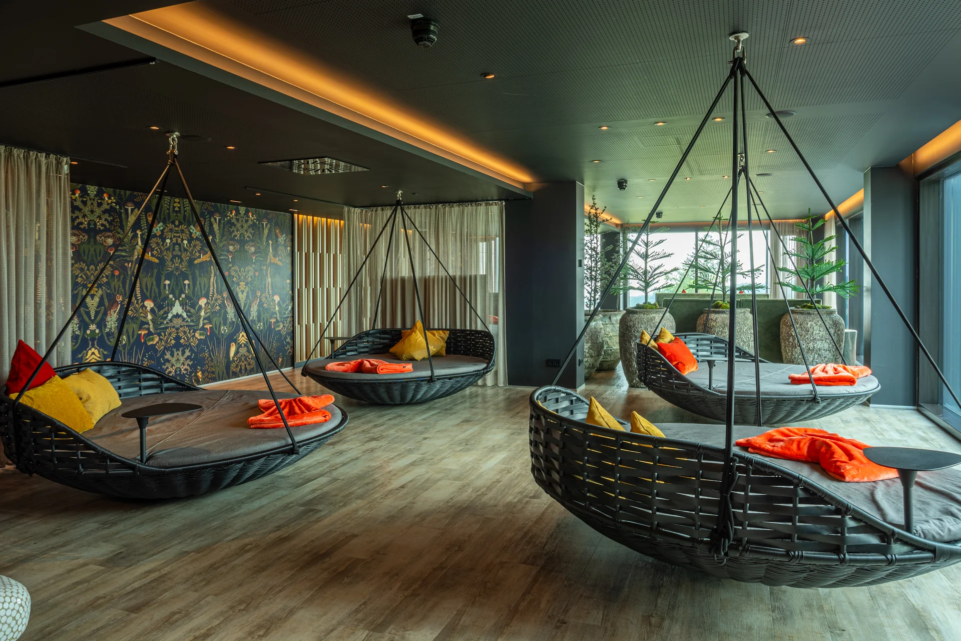 Moderner Lounge-Bereich mit Hängesesseln und bunten Kissen