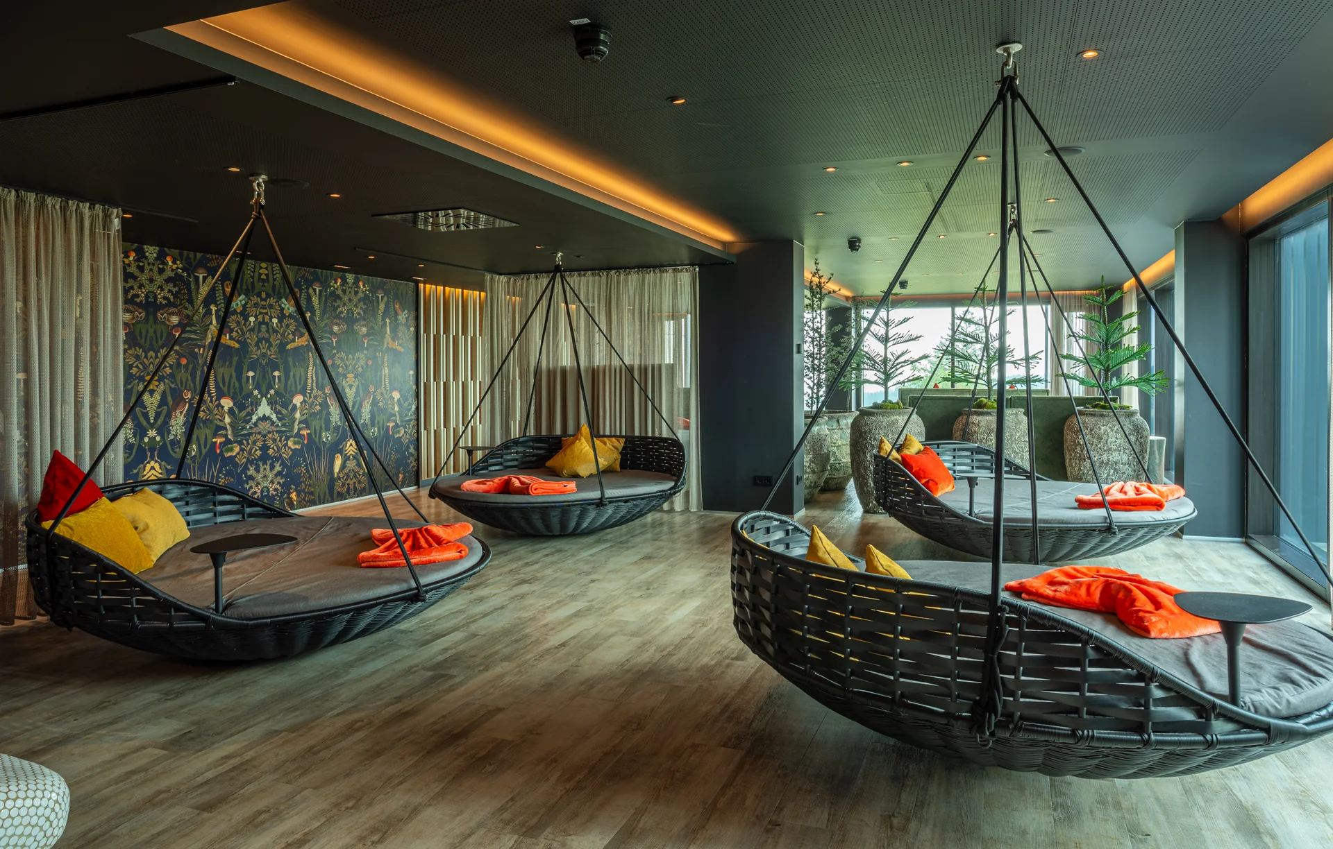 Moderner Lounge-Bereich mit Hängesesseln und bunten Kissen