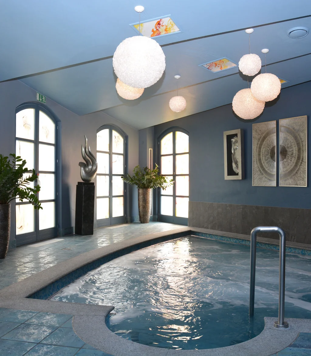 Innenpool mit blauen Wänden, modernen Lampen und Pflanzen