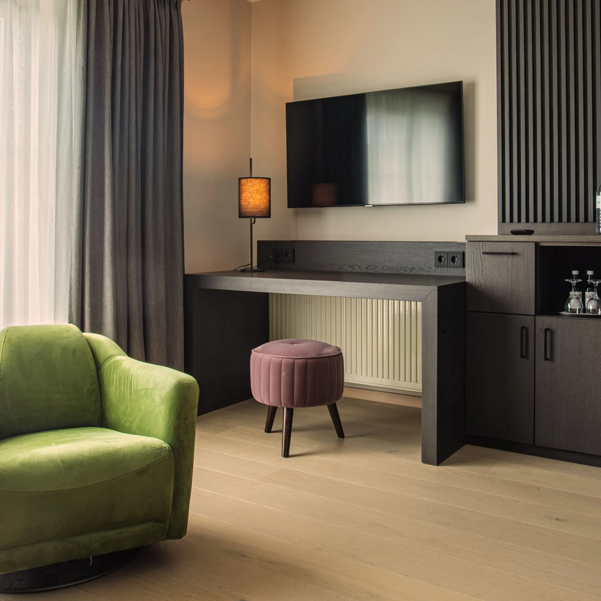 Moderner Wohnbereich mit grünem Sessel, TV und dunklen Holzmöbeln
