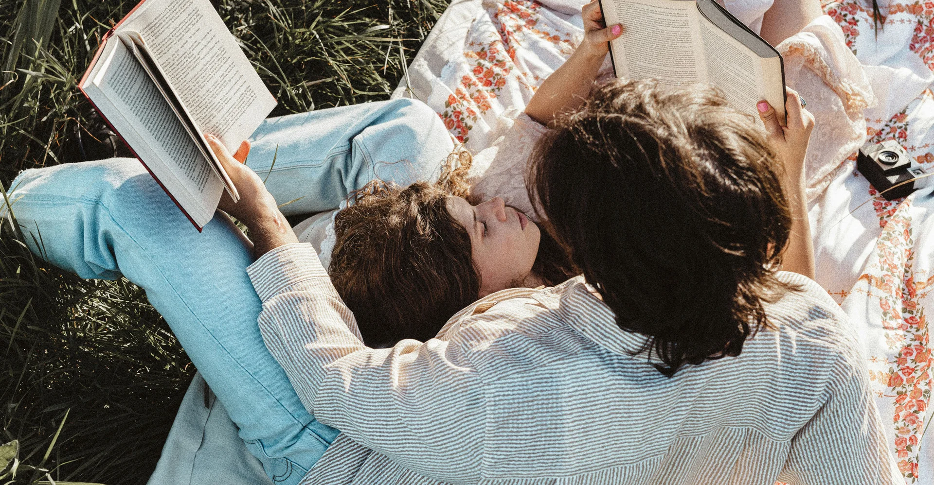 Zwei Frauen lesen Bücher entspannt auf einer Wiese auf einer Decke