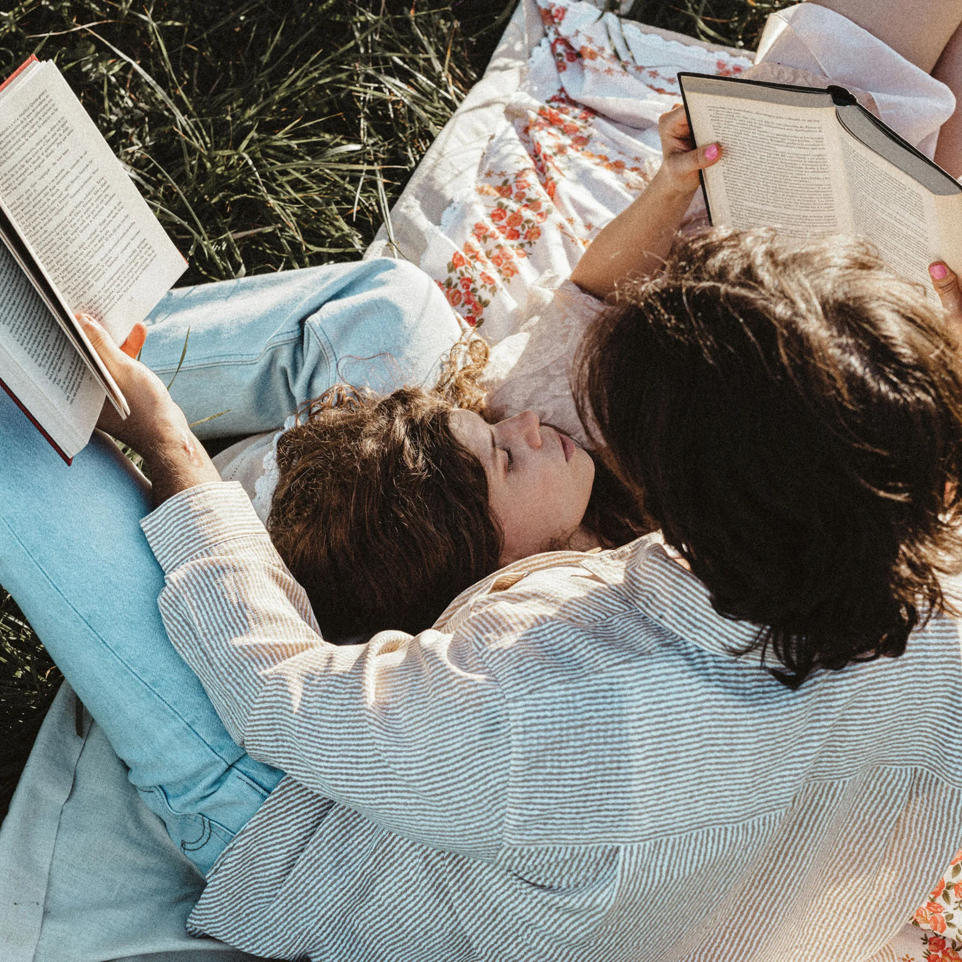 Zwei Frauen lesen Bücher entspannt auf einer Wiese auf einer Decke