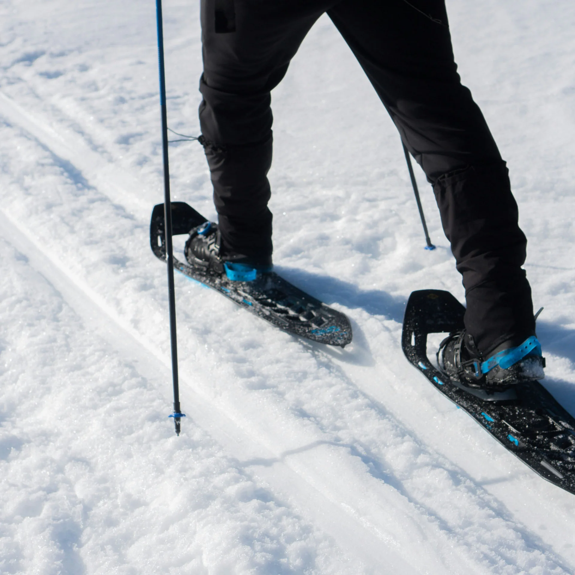 Person läuft mit Schneeschuhen und Stöcken im Schnee