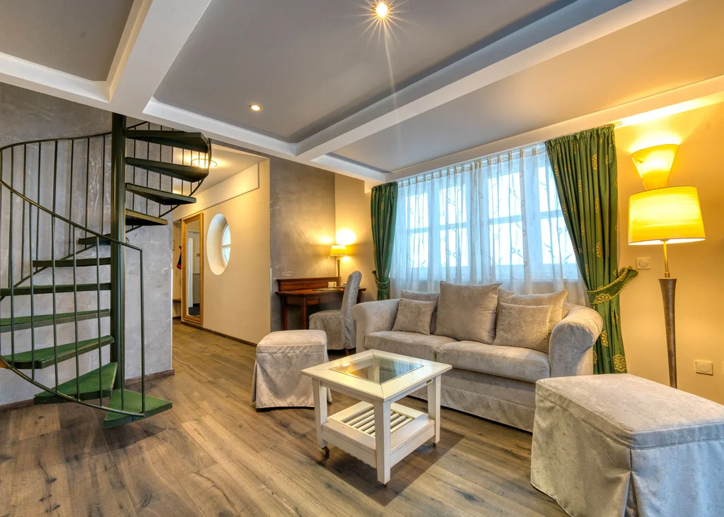 Gemütliches Wohnzimmer mit Wendeltreppe, Sofa und großem Fenster