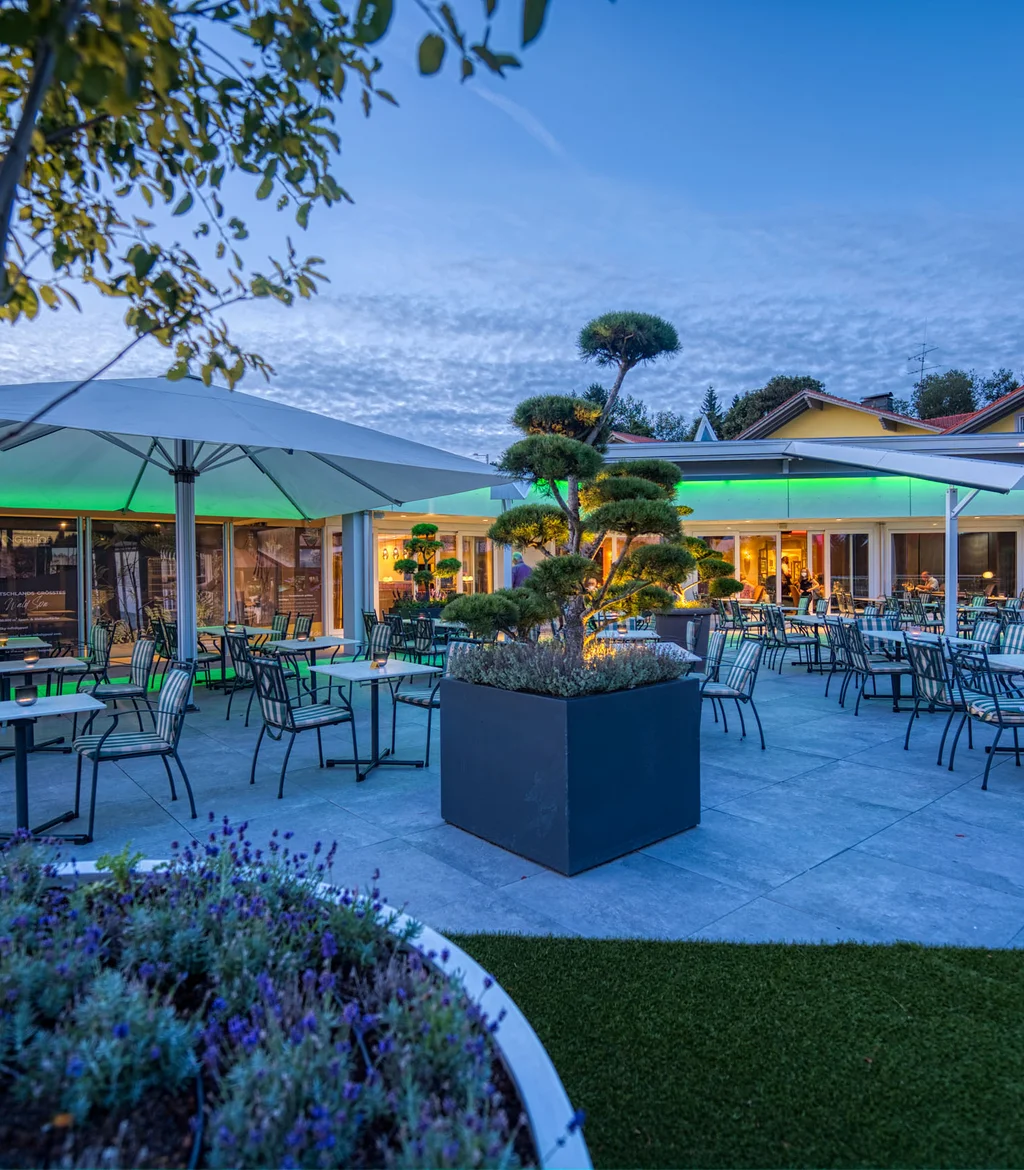 Abendliche Außenansicht eines modernen Restaurants mit Terrasse und Stühlen