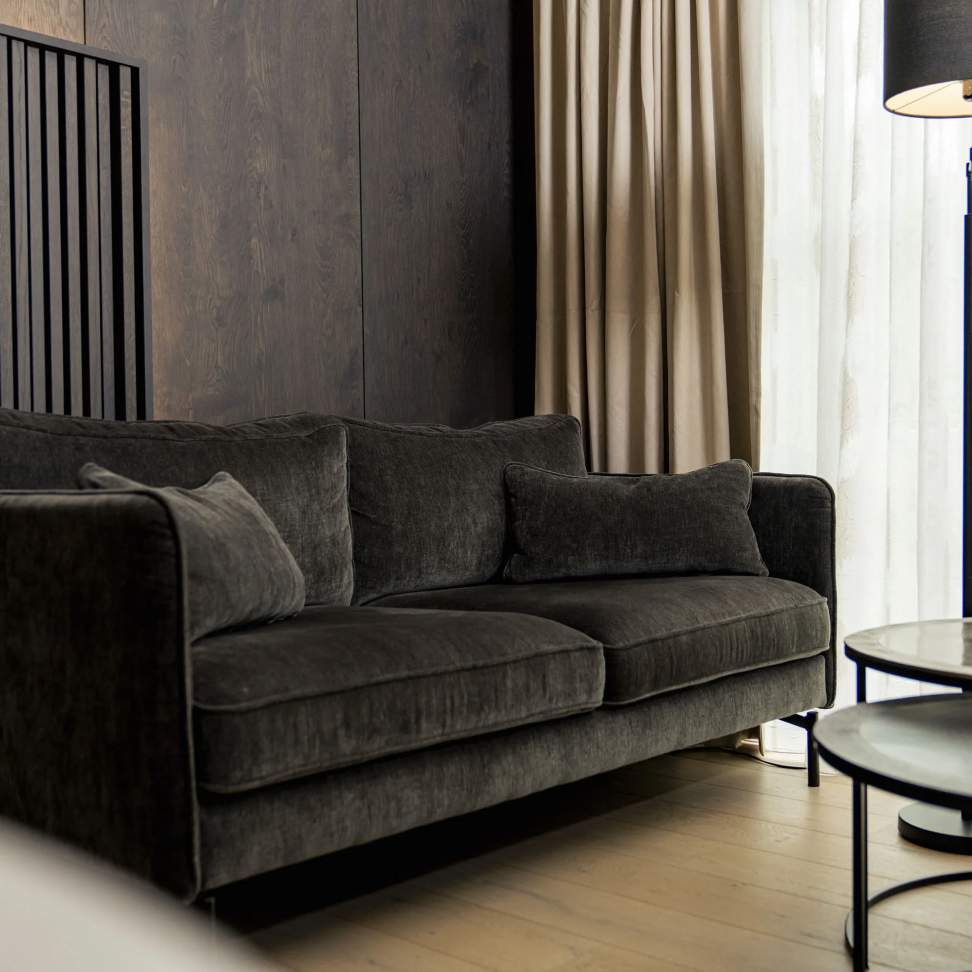 Moderner Wohnzimmerbereich mit dunklem Sofa, Stehlampe und Marmortisch
