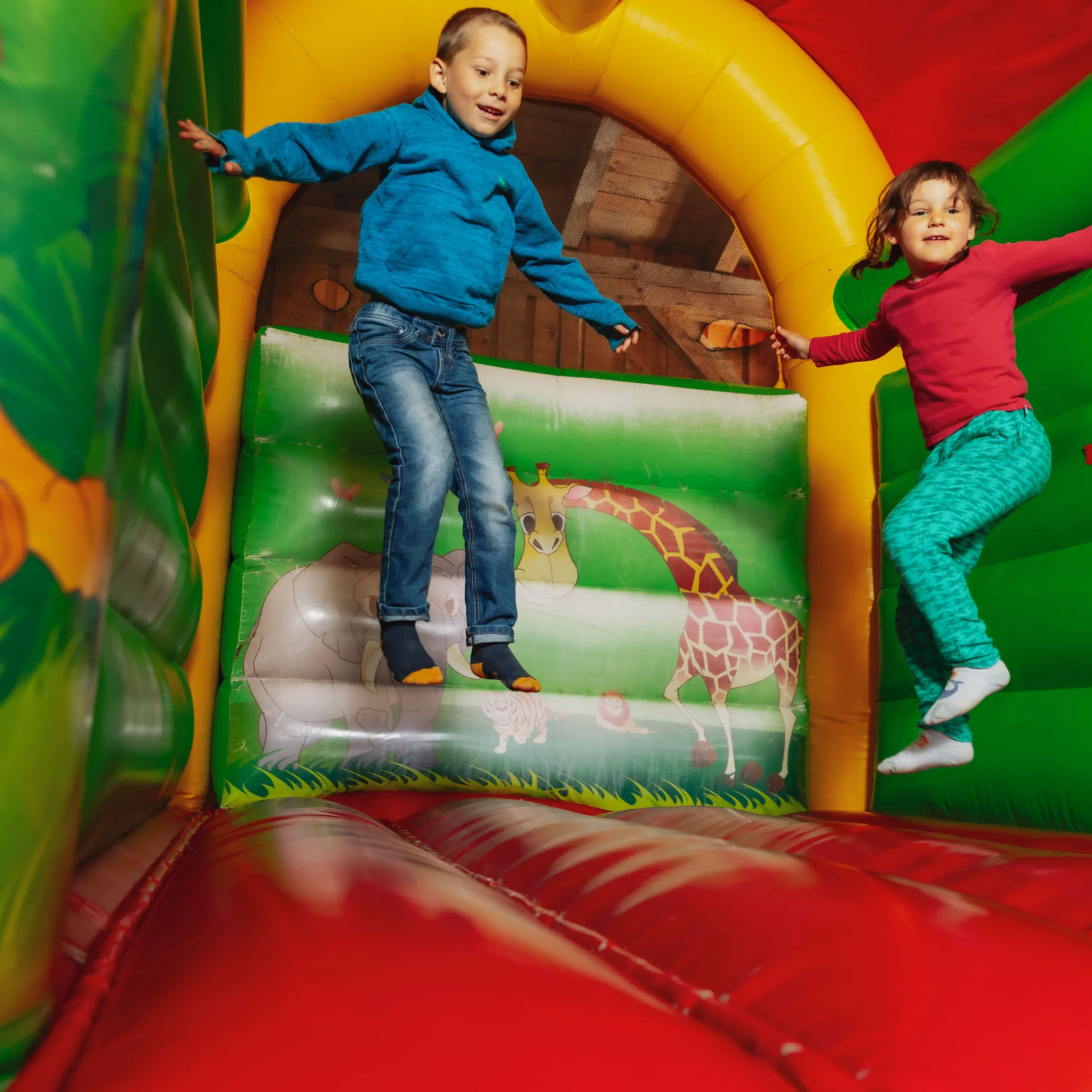 Zwei Kinder springen in einer bunten Hüpfburg